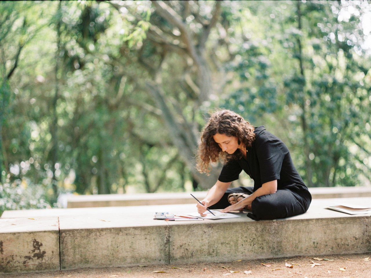 Person drawing in a stone bench in the middle of the forest